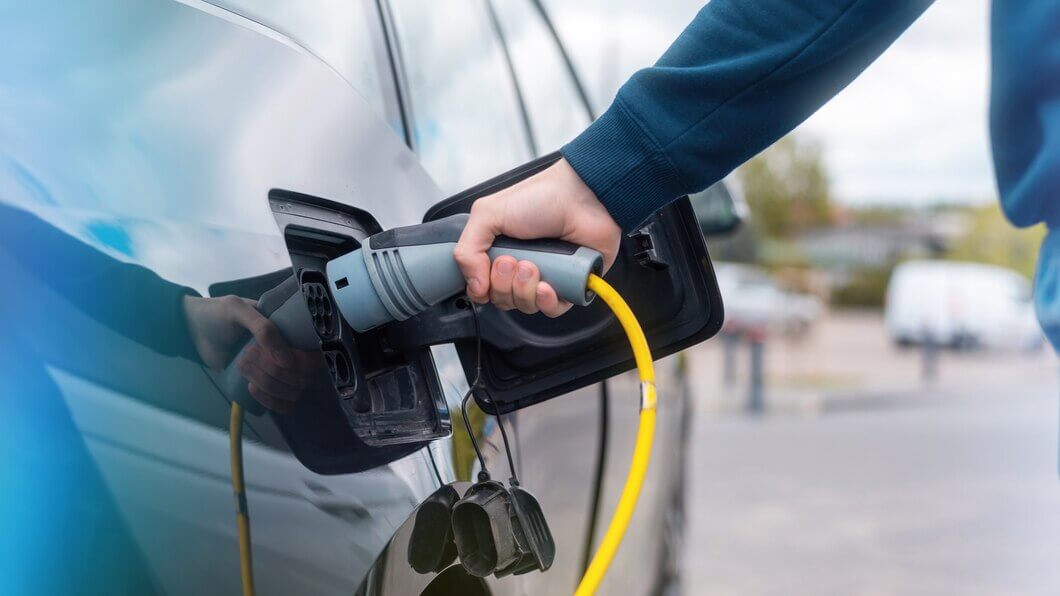 man plugging charger into electric car charge station 1268 17721